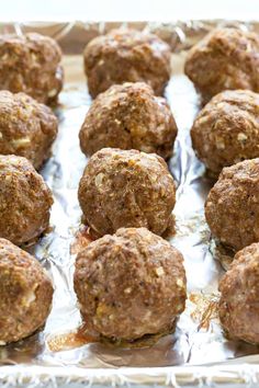 meatballs are sitting on top of foil in a baking pan, ready to be cooked