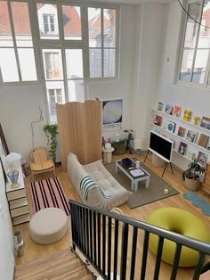 a living room filled with lots of furniture and large windows above the stairs to another room