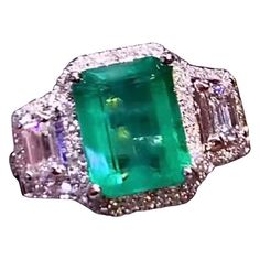 An exquisite Art Deco design, so gorgeous and chic, a very glamour ring handmade, in 18k gold with a natural Zambia emerald of 3,43 carats, fine quality, and 2 pieces of emerald cut diamonds and round brilliant cut diamonds of 1,04 carats, F/VS( top quality). Handcrafted by artisan goldsmith. Excellent manufacture and quality. Complete with AIG report. Whosale price. Note: on my shipment, customers NOT PAY TAXES and DUTY. Luxury Green Sapphire Ring Gia Certified, Green Gia Certified Luxury Sapphire Ring, Green Gia Certified Sapphire Ring, Formal Green Sapphire Ring With Diamond, Formal Green Sapphire Diamond Ring, Luxury Diamond Ring With Emerald Accent Stones, Exquisite Emerald Cut Emerald Ring, Elegant Green Sapphire Ring Gia Certified, Exquisite Green Diamond Ring With Brilliant Cut