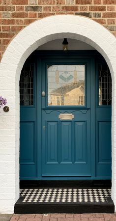 a blue front door with checkered flooring and white brick arch on the side