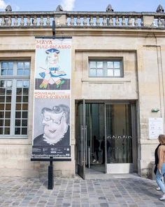 a woman walking past a building with an advertisement on the front and side of it