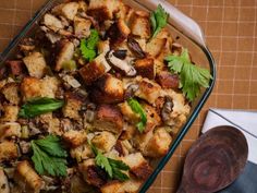 a casserole dish with bread, mushrooms and parsley in it on a table