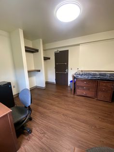 an empty room with a bed, desk, and chair in it's corner