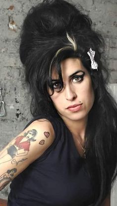 a woman with long black hair and tattoos on her arm