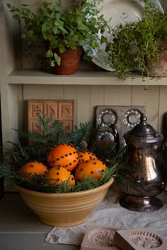 oranges in a bowl on a table next to a teapot and other items