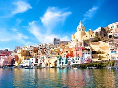 colorful buildings on the shore of a body of water with blue skies in the background