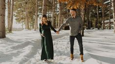 a man and woman holding hands in the snow