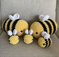 two crocheted stuffed animals sitting next to each other on a couch with pillows