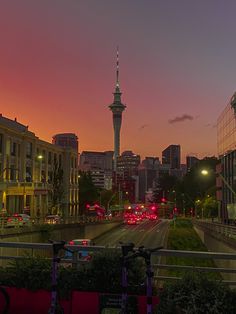 the sun is setting over a city with tall buildings and cars driving down the street