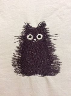 a white t - shirt with a black cat drawn on it's chest and eyes