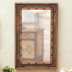 a mirror sitting on top of a table next to a potted plant and vase