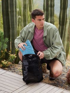 a man kneeling down next to a black bag with a blue item in it's pocket