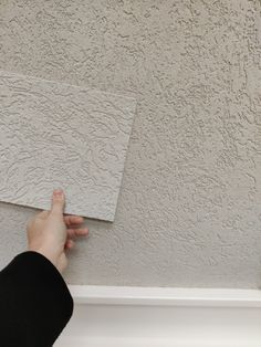 a person is painting the ceiling with white paint and a square piece of paper in front of them