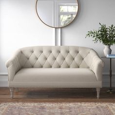 a white couch sitting on top of a wooden floor next to a table with a potted plant