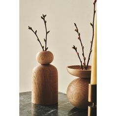 two wooden vases with flowers in them on a table next to a candle holder