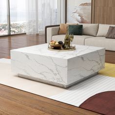 a white marble coffee table sitting on top of a wooden floor next to a couch