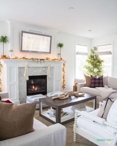 a living room filled with furniture and a fire place under a christmas tree in the corner