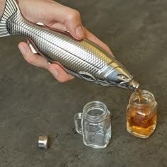 a person is holding a fish shaped object in front of some glass jars and nuts