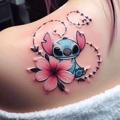 a woman with a tattoo on her back has a pink flower in the shape of a cartoon character