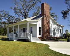 a small white house sitting on top of a lush green field