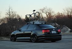 a car with a bike on top of it's roof rack in a parking lot