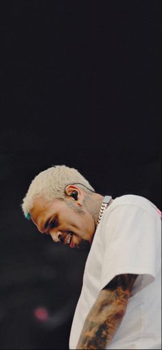 a man with white hair and piercings on his face is looking down at something