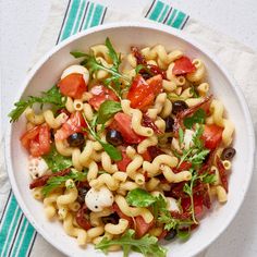 a white bowl filled with pasta salad on top of a blue and white table cloth