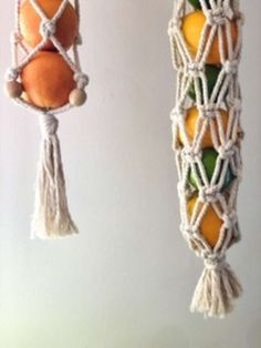 three hanging fruit baskets with oranges, lemons and an egg in them on hooks