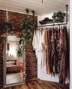 a room filled with lots of clothes hanging on a rack next to a brick wall