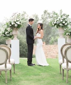 a bride and groom standing in front of chairs