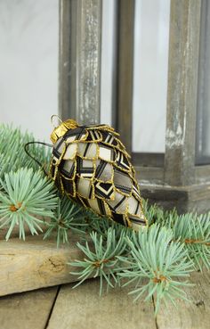 an ornament sitting on top of a wooden table next to pine cones and needles