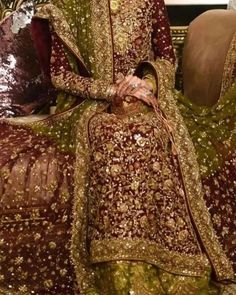 a woman sitting on top of a couch wearing a green and gold dress