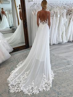 a woman standing in front of a mirror wearing a wedding dress