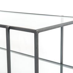 an empty glass table with metal legs on the bottom and sides, against a white background