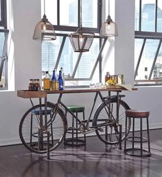 two bicycles are parked in front of a table with bottles and glasses on it, near large windows