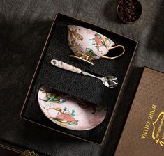 an empty box with two tea cups and spoons in it next to other items