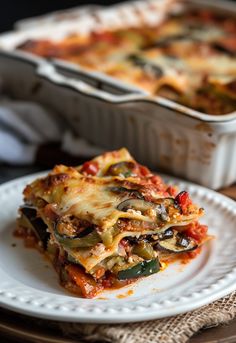 a white plate topped with lasagna next to a casserole dish