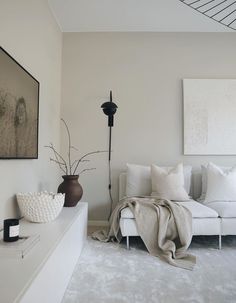 a living room filled with white furniture and pillows on top of a couch next to a painting