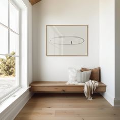 a wooden bench sitting in front of a window next to a painting on the wall