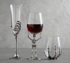 three wine goblets and one glass with red wine in it on a table