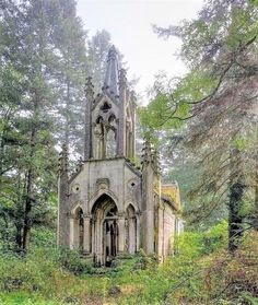 an old church in the middle of a forest with trees and grass on both sides