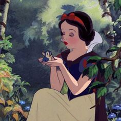 snow holding a frog in her hands while sitting on a tree branch with leaves around her