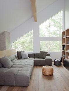 a living room with a large gray couch and book shelf on the wall next to it