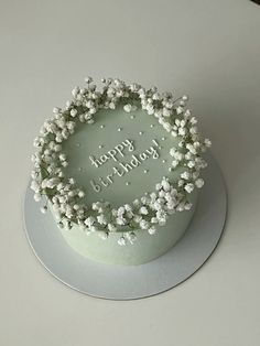 a birthday cake decorated with white flowers and the words happy birthday written in frosting