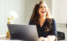 a smiling woman sitting in front of a laptop computer