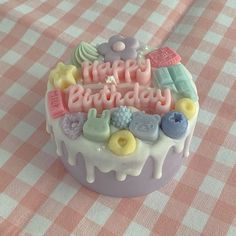 a birthday cake on a checkered tablecloth with the words happy birthday spelled in frosting