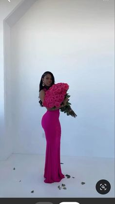 a woman in a pink dress holding a large bouquet of flowers and posing for the camera