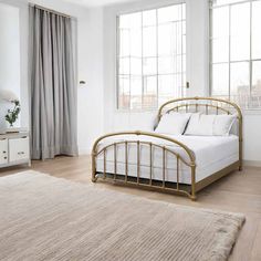 a bedroom with white walls and wooden floors, a bed frame in the foreground