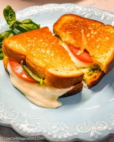 a grilled cheese sandwich with tomato and lettuce on a light blue plate