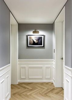 an empty room with wood floors and white walls, framed artwork on the wall above it